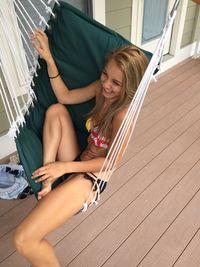 Smiling young woman bikini while sitting on hammock