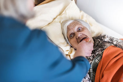 Woman taking care of old woman lying in bed