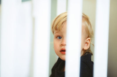 Close-up portrait of cute baby girl in crib at home