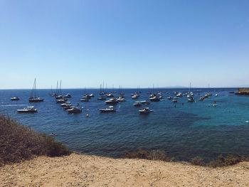 Sailboats in sea against clear blue sky