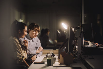 Multiracial female colleagues discussing over laptop while working late at work place