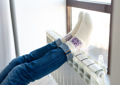 Legs of woman on radiator at home