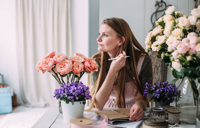 Young woman with flower vase on table