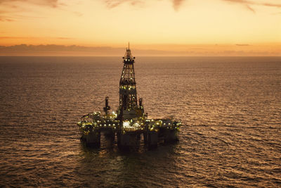 High angle view of oil rig in sea during sunset