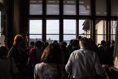 Rear view of people looking through window