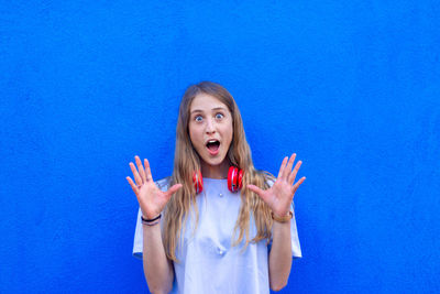 Portrait of young woman against blue background