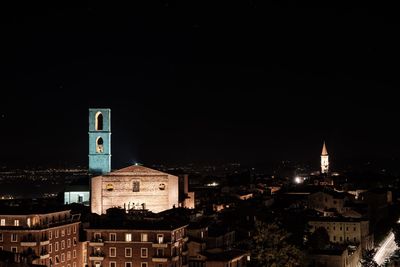 Illuminated buildings in city against clear sky at night