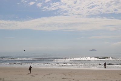 Boy playing with ball at beach against sky