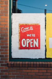 Come in we're open hand painted restaurant sign in window brick wall covid-19 pandemic