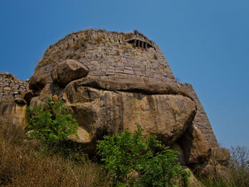 Low angle view of rock formation against clear blue sky