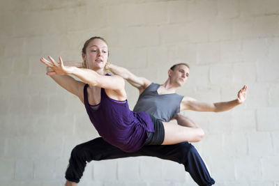 Ballet dancers practicing against wall in studio
