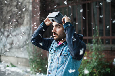 Young man using virtual reality simulator during snowfall