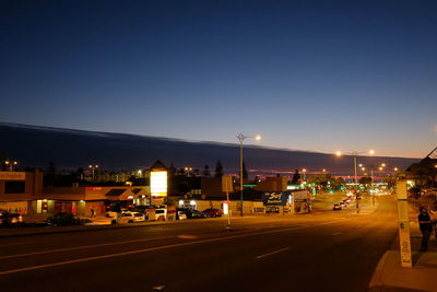 Illuminated city street against clear sky at night