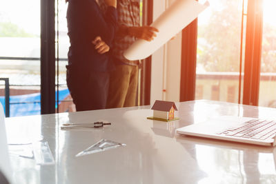 Midsection of woman standing by window at home