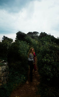 Woman standing by tree against sky