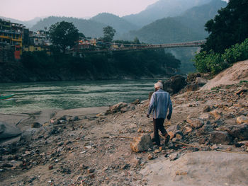 Rear view of man standing on rocks against mountains