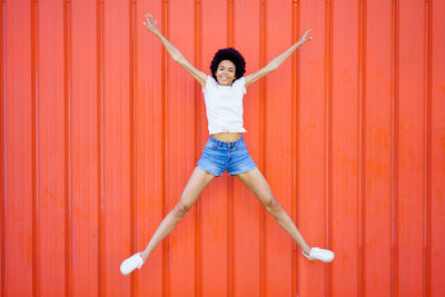 Full length of woman standing against yellow wall