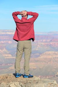 Rear view of man looking at grand canyon while standing on rock