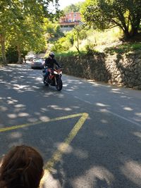 Rear view of people riding motorcycle on road