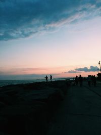 Silhouette people on beach against sky during sunset