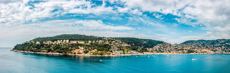 Scenic view of town by sea against sky