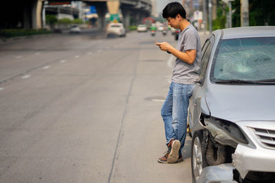 Full length of man using mobile phone while standing on street