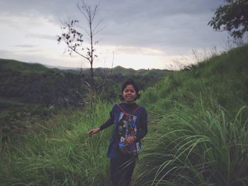 Portrait of smiling girl standing on field against sky