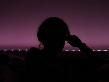 Rear view of woman sitting on sofa against sky during sunset