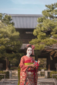 Portrait of young woman standing against built structure