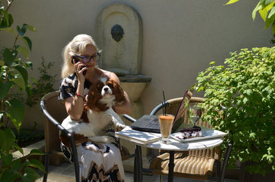 Business woman on holidays elegantly dressed talking on a cell phone while petting her lapdog