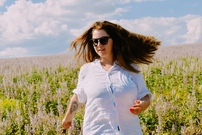 Young woman wearing sunglasses while standing on field