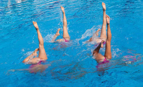 Swimmers with feet up swimming in pool