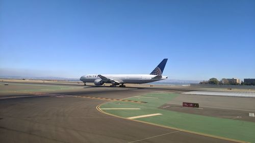 Airplane on airport runway against clear blue sky