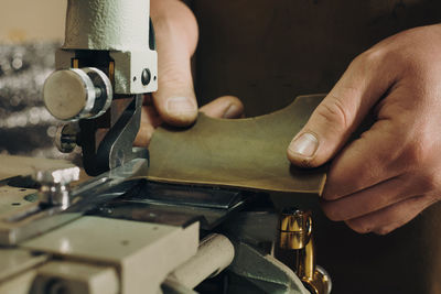 Machining leather in workshop. cropped view of the man hands holding leather and cutting