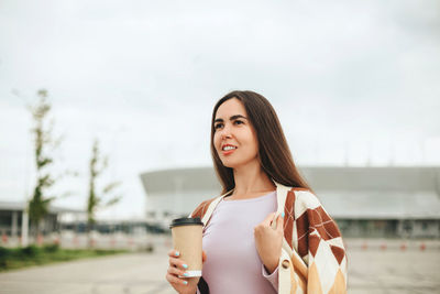 Portrait of young woman standing against sky