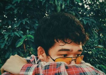 Close-up of man wearing sunglasses against plants