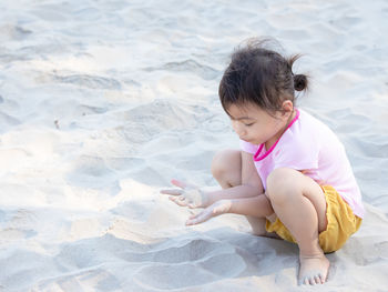 Side view of girl playing with ball on sand at beach
