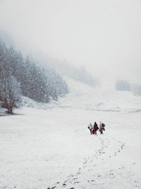 People in snow against sky during winter