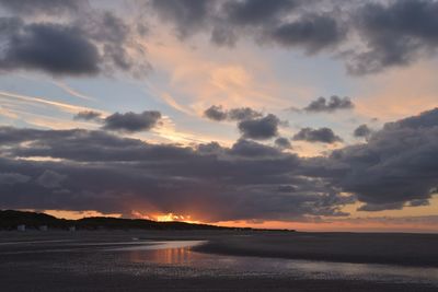 Scenic view of sea against dramatic sky during sunset