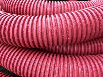 Pile of plastic pipes wet from the rain, corrugated burgundy pipes, magenta