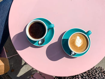 Morning coffees on pink table. morning coffees in tiffany color ceramic mugs with saucers on pink