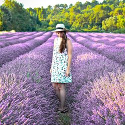 Full length of woman standing on flowering plant field