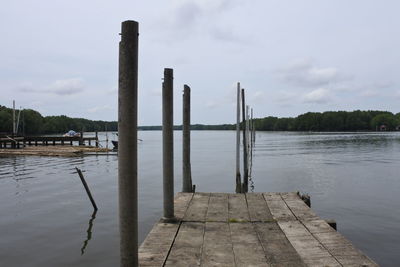 Wooden posts in lake against sky