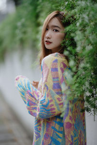 Portrait of young woman standing against plants