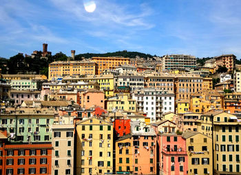 High angle view of residential buildings in city against blue sky