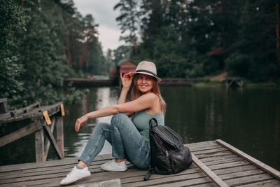 Young girl in a blue top on vacation in a hike with a backpack by the lake in the forest area