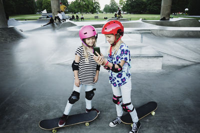 Girl showing mobile phone to friend while standing at skateboard park