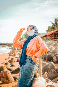 Woman standing at beach against sky