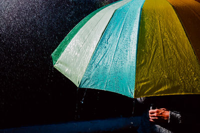 Midsection of person holding umbrella during rain