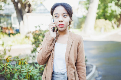 Young woman standing against trees